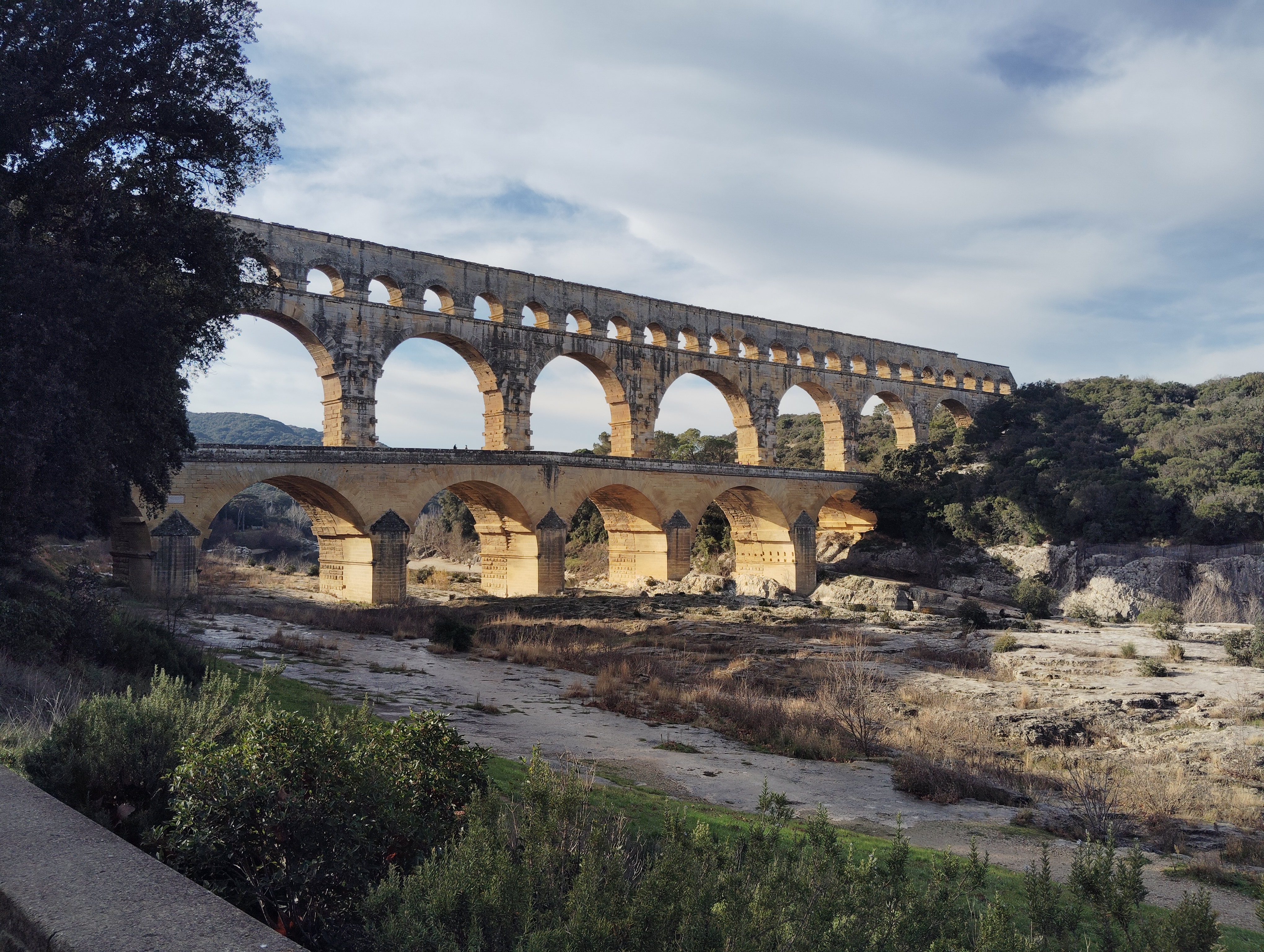 Vue du Pont du Gard avec la rivière et ses pierres jaunes, Gard, France.

View of Le Pont du Gard with the river and its yellow stones, Gard, France.