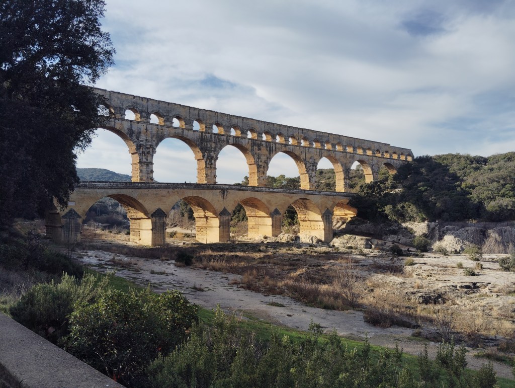 Vue du Pont du Gard avec la rivière et ses pierres jaunes, Gard, France.

View of Le Pont du Gard with the river and its yellow stones, Gard, France.

